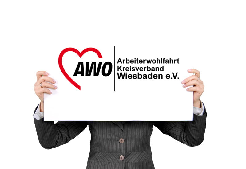 Eine Frau hält ein Plakat vor ihrem Gesicht auf dem das Logo der AWO Wiesbaden zu sehen ist