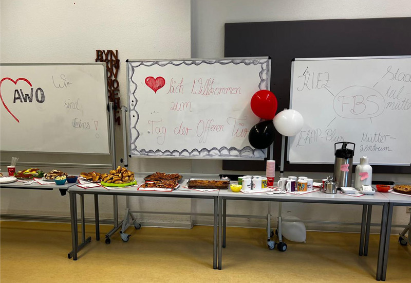 Essen und Getränke stehen auf einem großen Tisch und an der Wand hängen Luftballons
