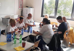 Helferinnen und Helfer der AWO Wiesbaden sitzen gemeinsam am Tisch während einer Pause ihres ehrenamtlichen Einsatzes