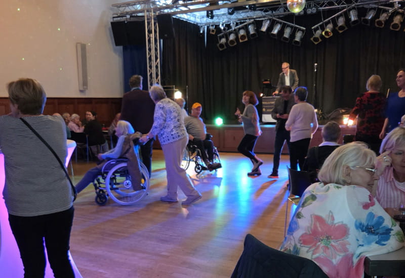 Teilnehmende der Ü60-Party der AWO Wiesbaden tanzen und feiern gemeinsam im festlich beleuchteten Veranstaltungssaal