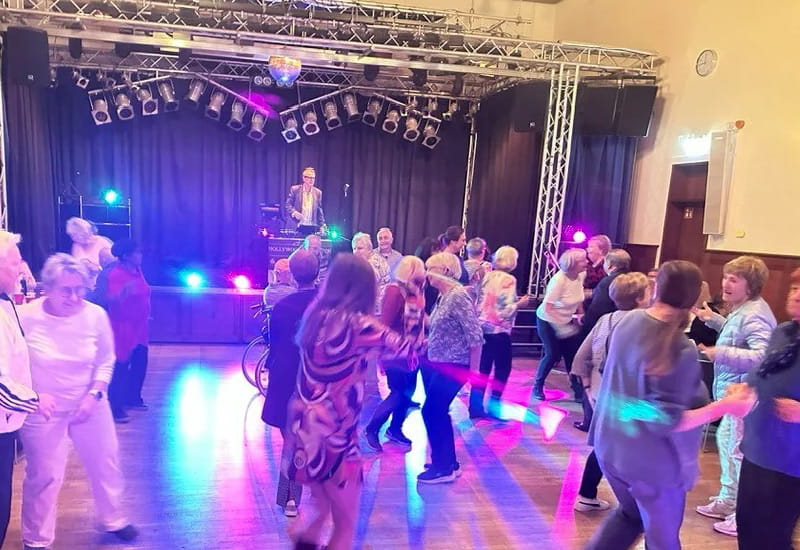Seniorinnen und Senioren tanzen ausgelassen bei der Ü60-Party der AWO Wiesbaden vor einer beleuchteten Bühne mit Live-Musik