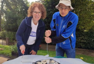 Zwei Teilnehmende bemalen gemeinsam ein großes Holzobjekt bei einem Projekt von Wiesbaden Engagiert