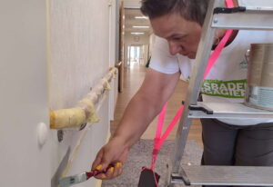 Teilnehmer von Wiesbaden Engagiert streicht einen Handlauf in einer sozialen Einrichtung in Wiesbaden