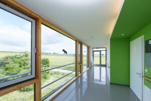 Breiter, heller Flur mit bodentiefen Panoramafenstern und Blick auf die umliegenden Felder im Robert Krekel Haus