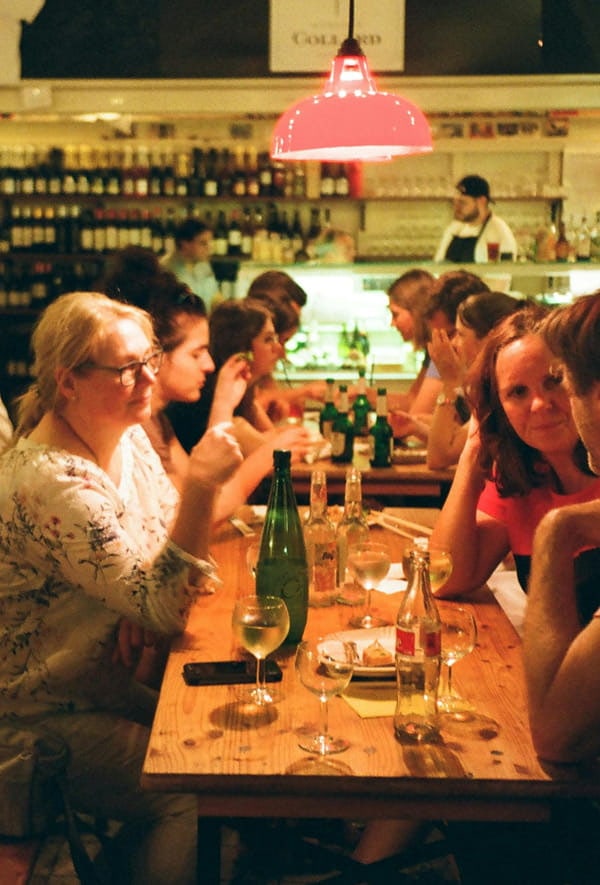 Gemeinsamer Austausch beim Essen Menschen sitzen gemeinsam an einem langen Tisch in einem Restaurant und unterhalten sich in geselliger Atmosphäre