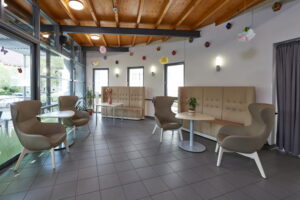 Freundlich gestalteter Aufenthaltsbereich im Robert Krekel Haus mit Sitzgruppen, Tischen und großen Fensterflächen