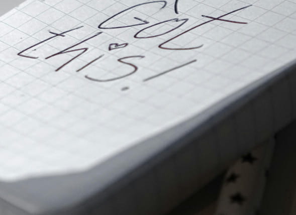 Nahaufnahme einer handschriftlichen motivierenden Notiz auf kariertem Papier als Symbol für Unterstützung und neue Perspektiven