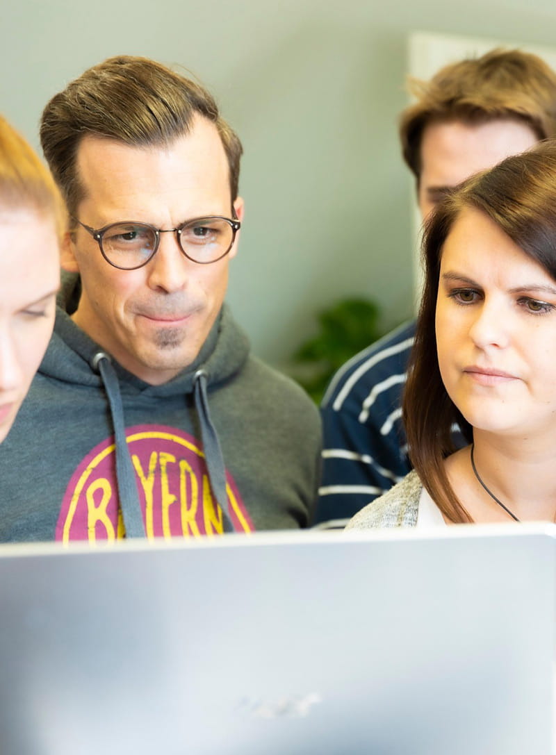 Eine Gruppe von Menschen blickt konzentriert auf einen Laptop-Bildschirm in der Bildungsstätte Wiesbaden – Symbol für digitale Kompetenz und gemeinsames Lernen bei der AWO