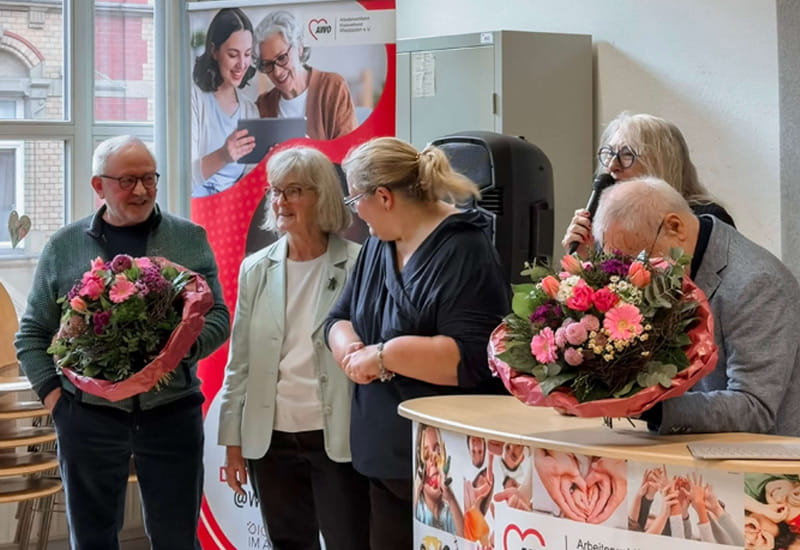Gruppenbild beim Kick Off der Digitallotsen in Wiesbaden mit Blumensträußen und Roll Up Banner im Hintergrund